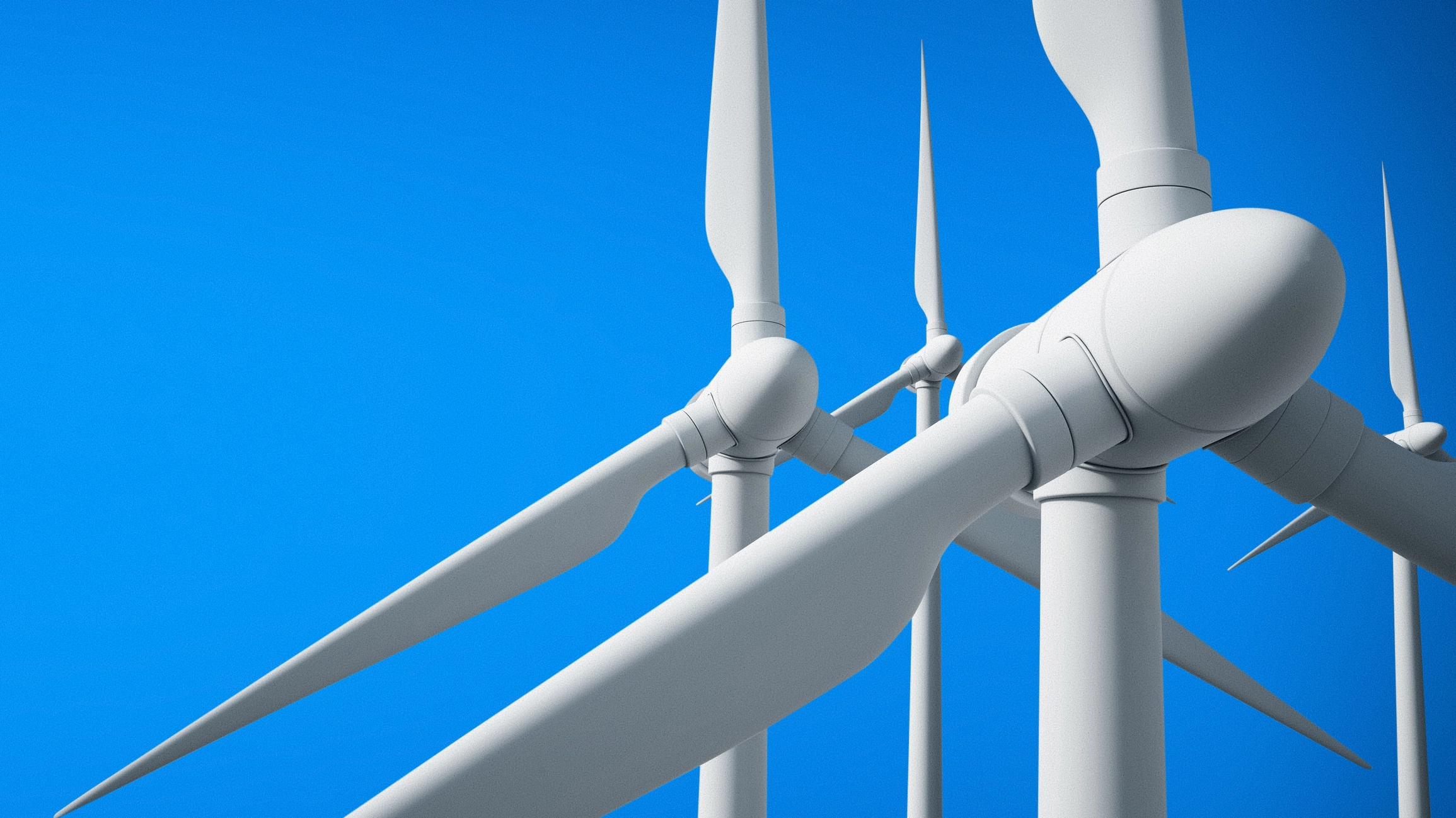 Close-up of white wind turbines against a clear blue sky.